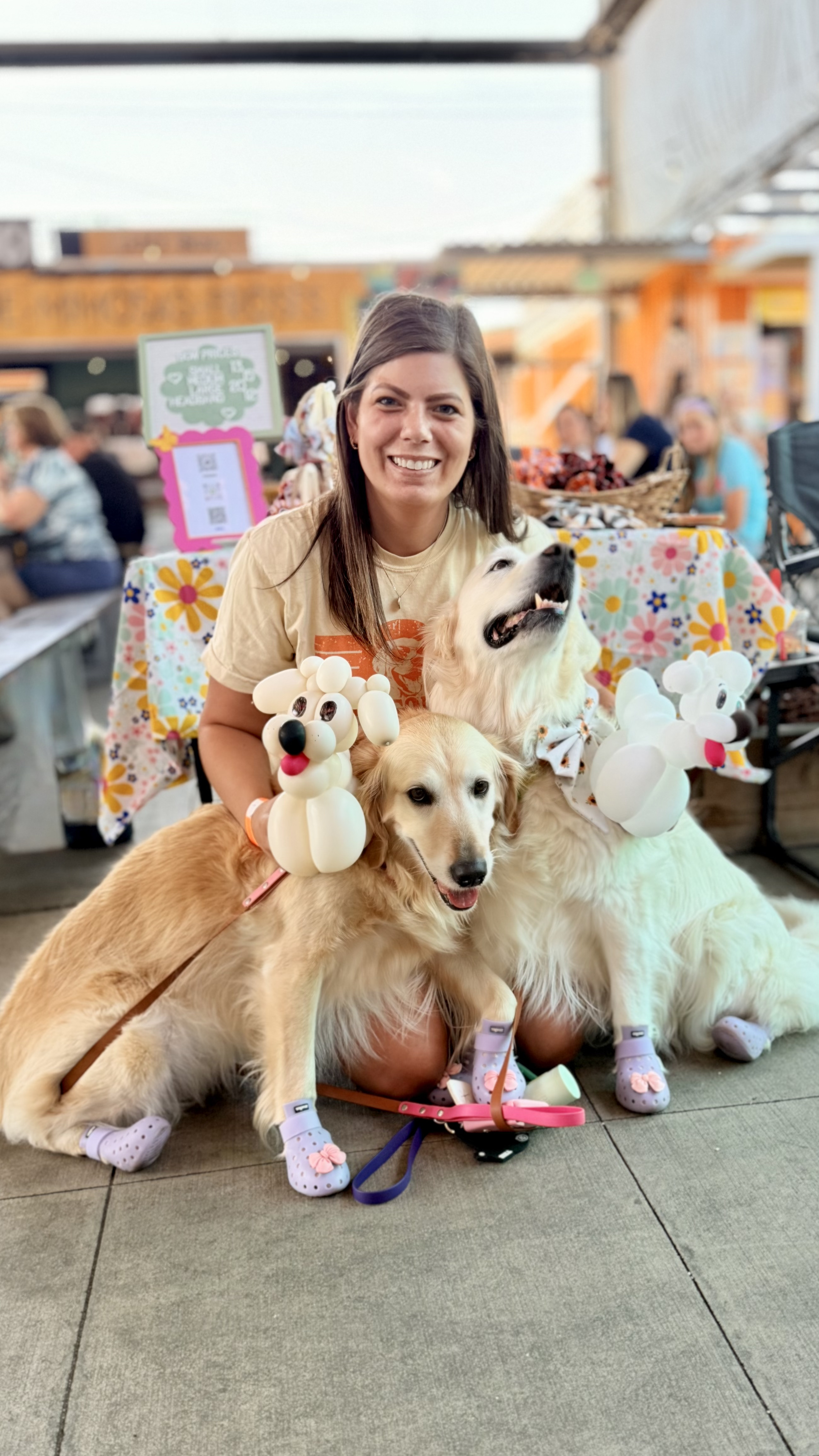 Jenny with Shayna, the darker golden, and Hopey, the lighter golden, at a Greenville market booth